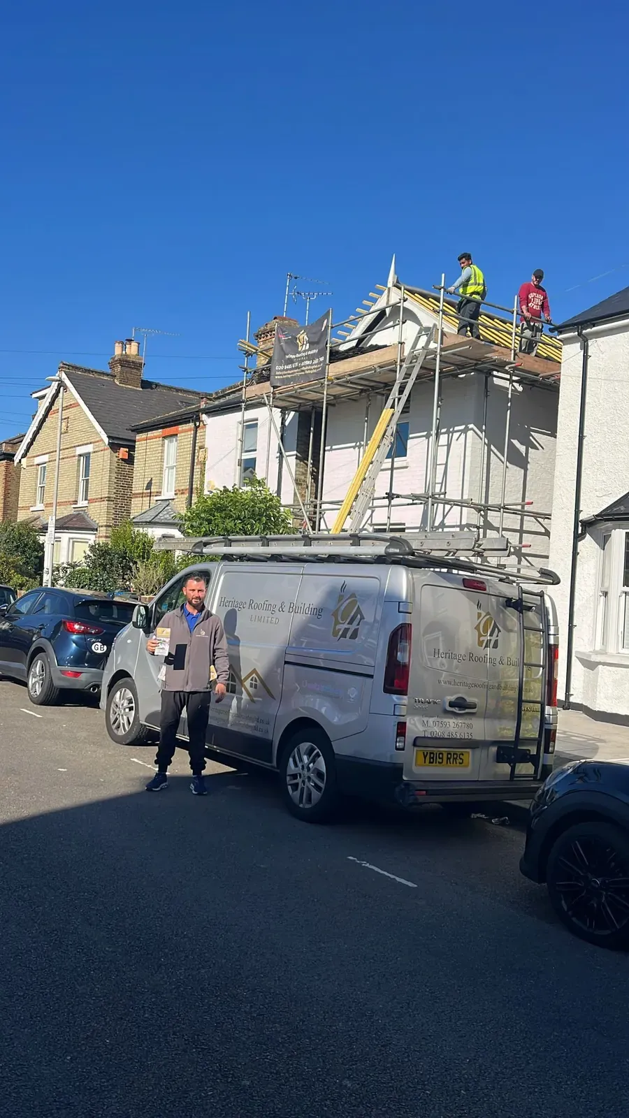 Heritage Roofing owner beside the van with scaffolding on the house behind