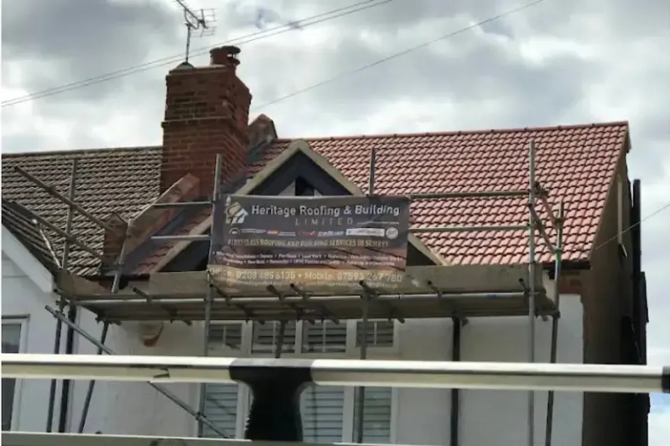 Scaffolding on a house with a Heritage Roofing sign board