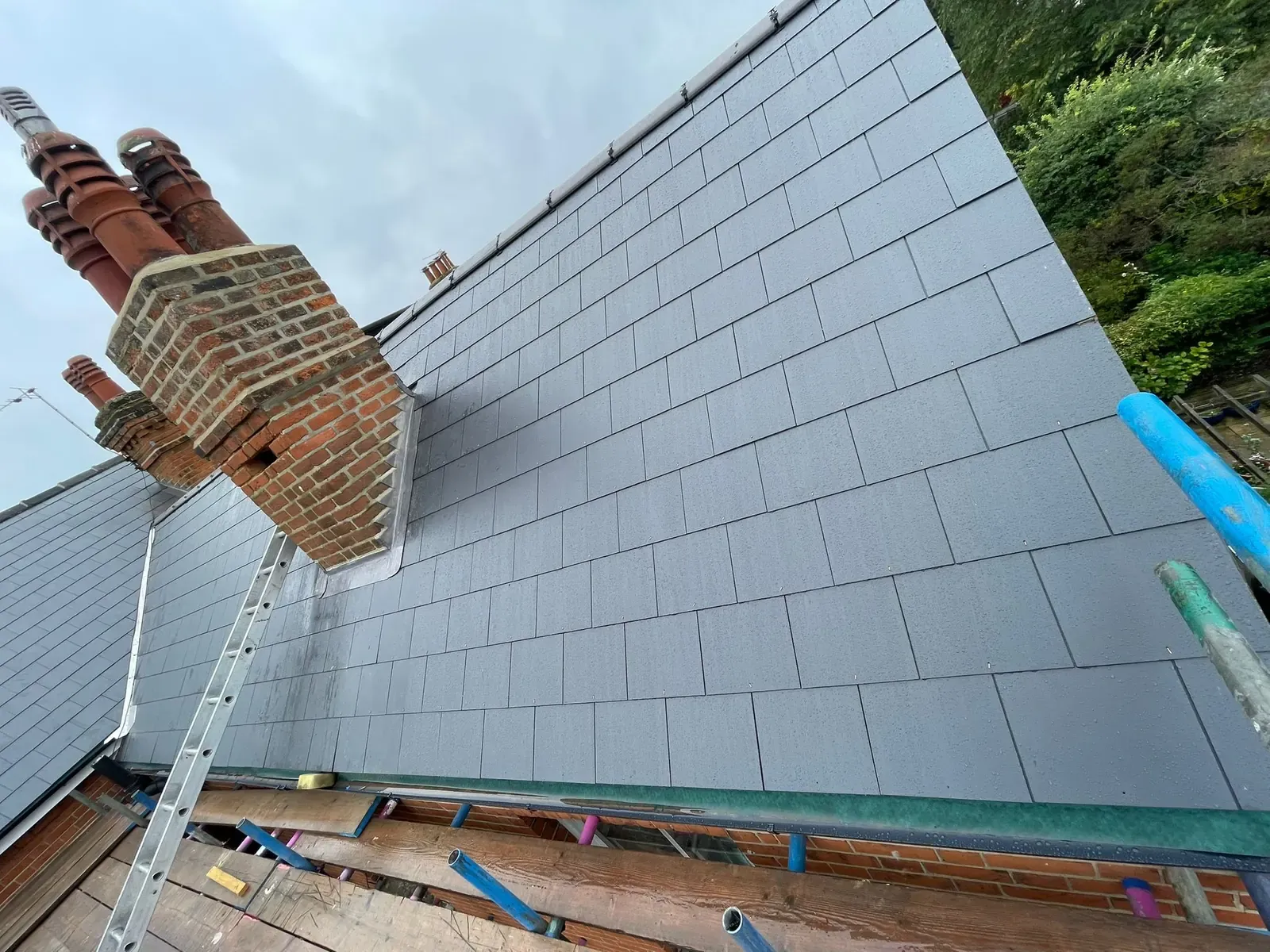 Fresh slates laid up to a brick chimney stack on a re-roof